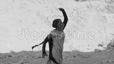女孩正在岩石附近<strong>的沙漠里</strong>跳舞。 黑白图像